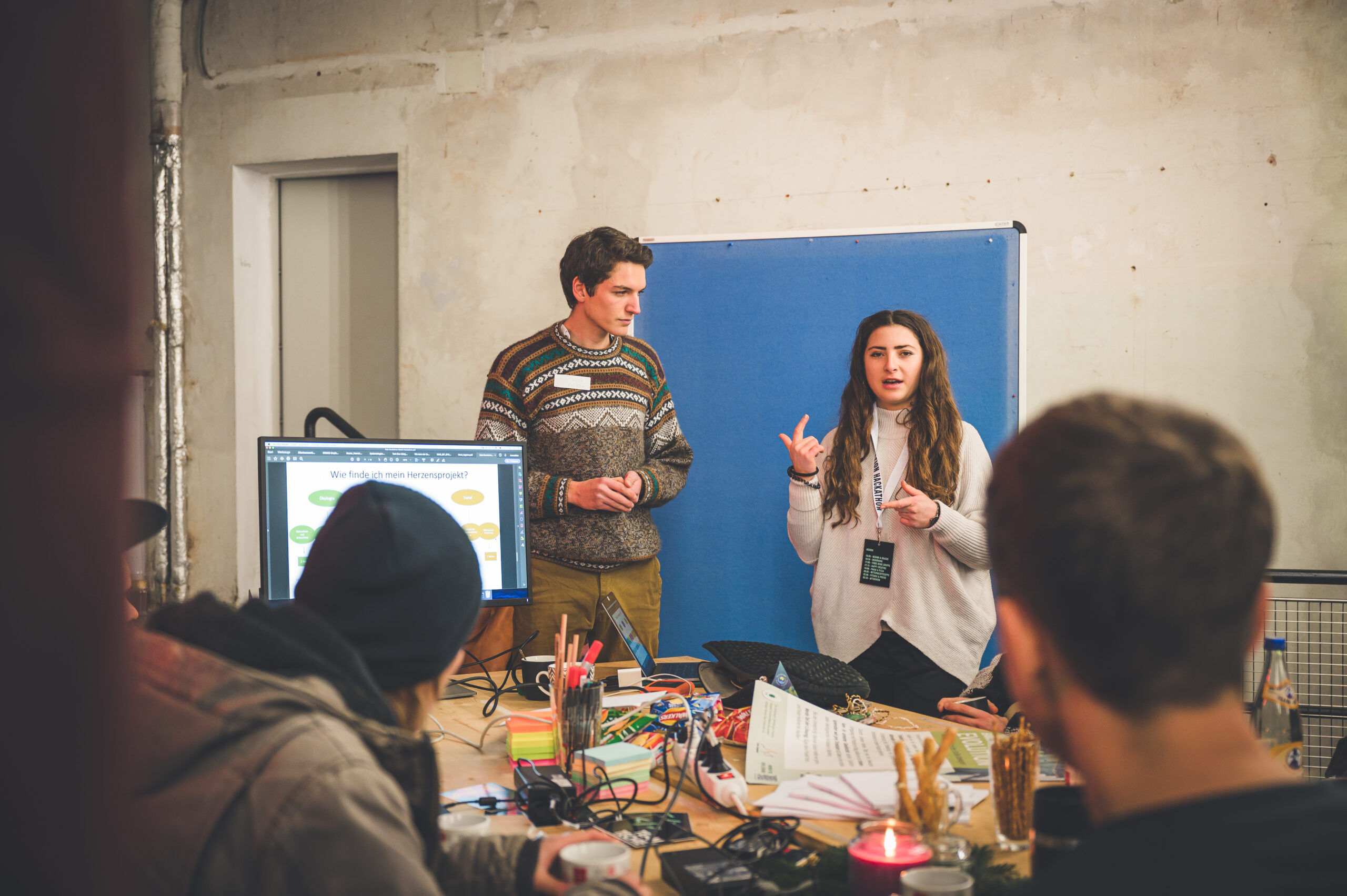 Zwischenpräsentation in einem Hackathon Team: Der Tisch sieht voll und nach Arbeit aus